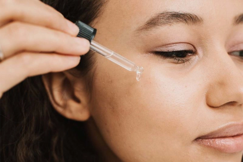 Woman applying serum to her cheek