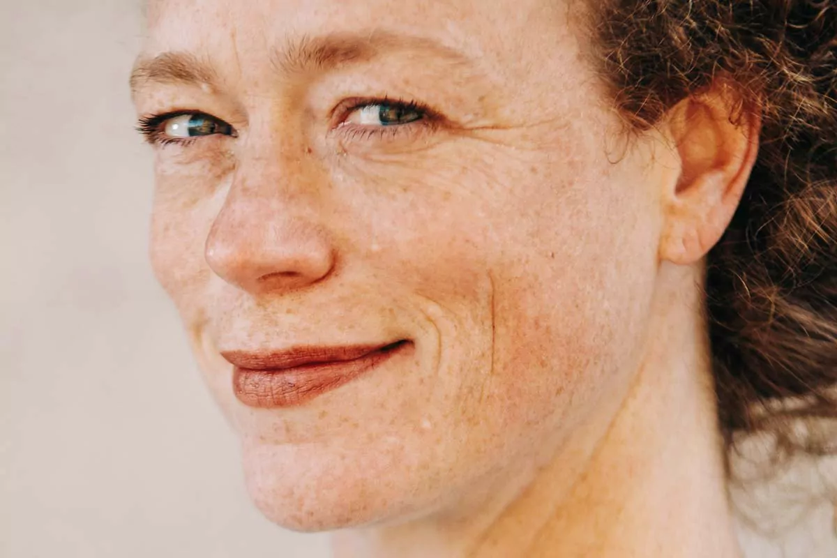 A close-up of a woman's face, capturing a gentle smile and a relaxed, content expression.