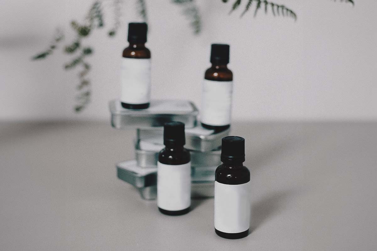 Skin care glass bottles with droppers containing skincare products or essential oils, are arranged on various levels.