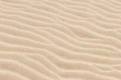 A close-up of wavy patterns in sand, likely formed by wind or water on a beach or desert.