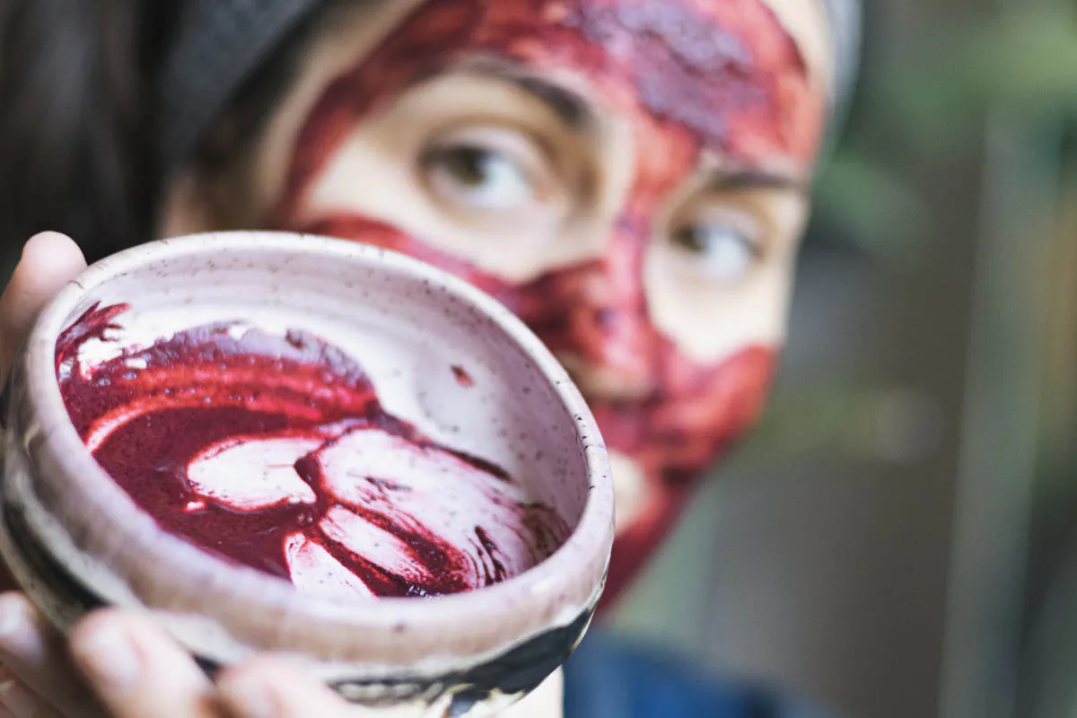Women wearing a bright fuschia mask and holding the bowl with the remaining mask mixture up to the camers