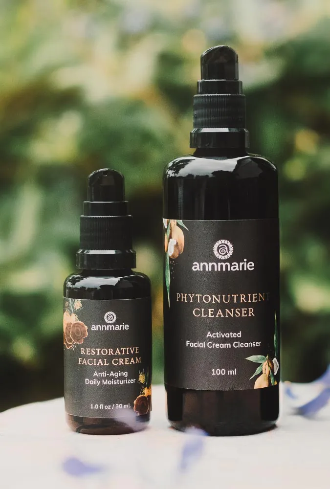 Restorative Facial & Neck Cream and Phytonutrient Cleanser against blurry natural background