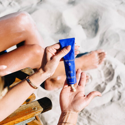 Woman squeezing chemical UV filter free salt+blue sunscreen into hand
