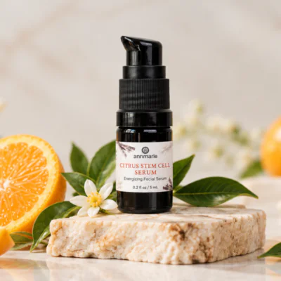 Citrus Stem Cell Serum on a stone pedestal with sliced orange in the background